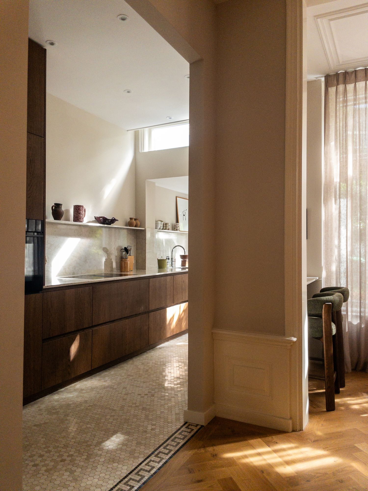 Doorkijk vanuit de hal naar een houten keuken met visgraatvloer in Den Haag