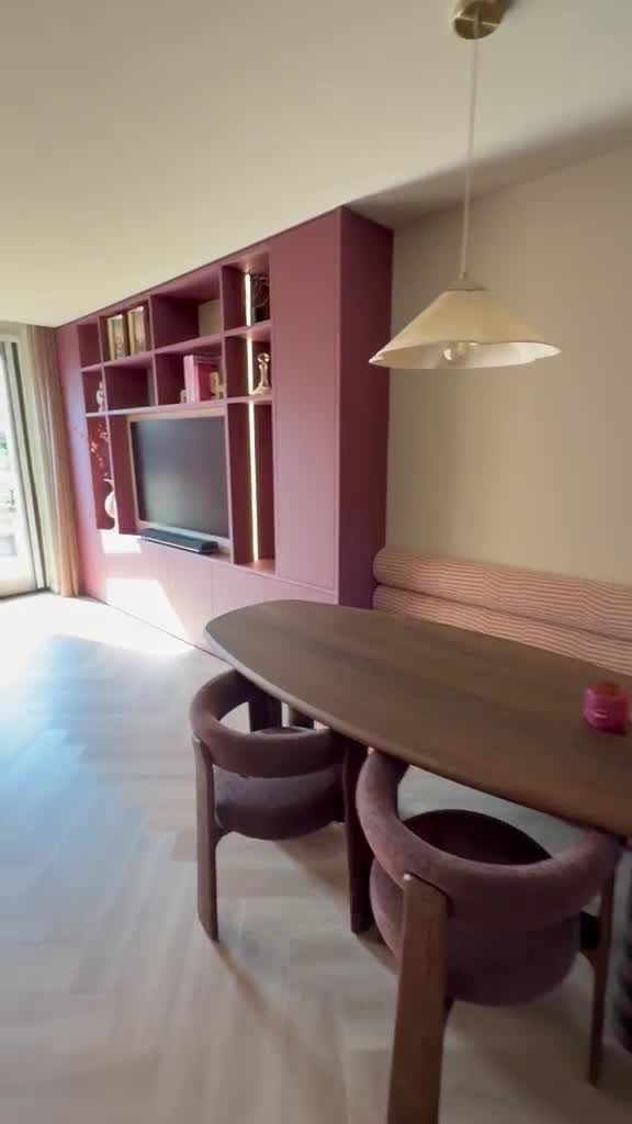 Bordeauxrode tv-kast met open vakken naast de eettafel in Schiedam